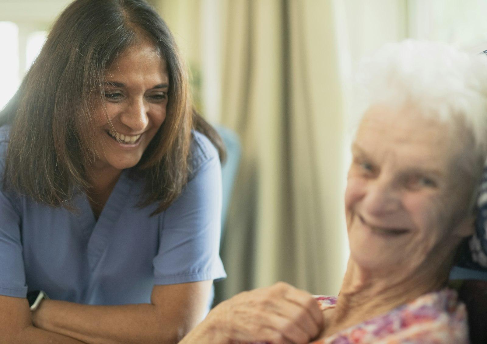 A caregiver smiles alongside a resident