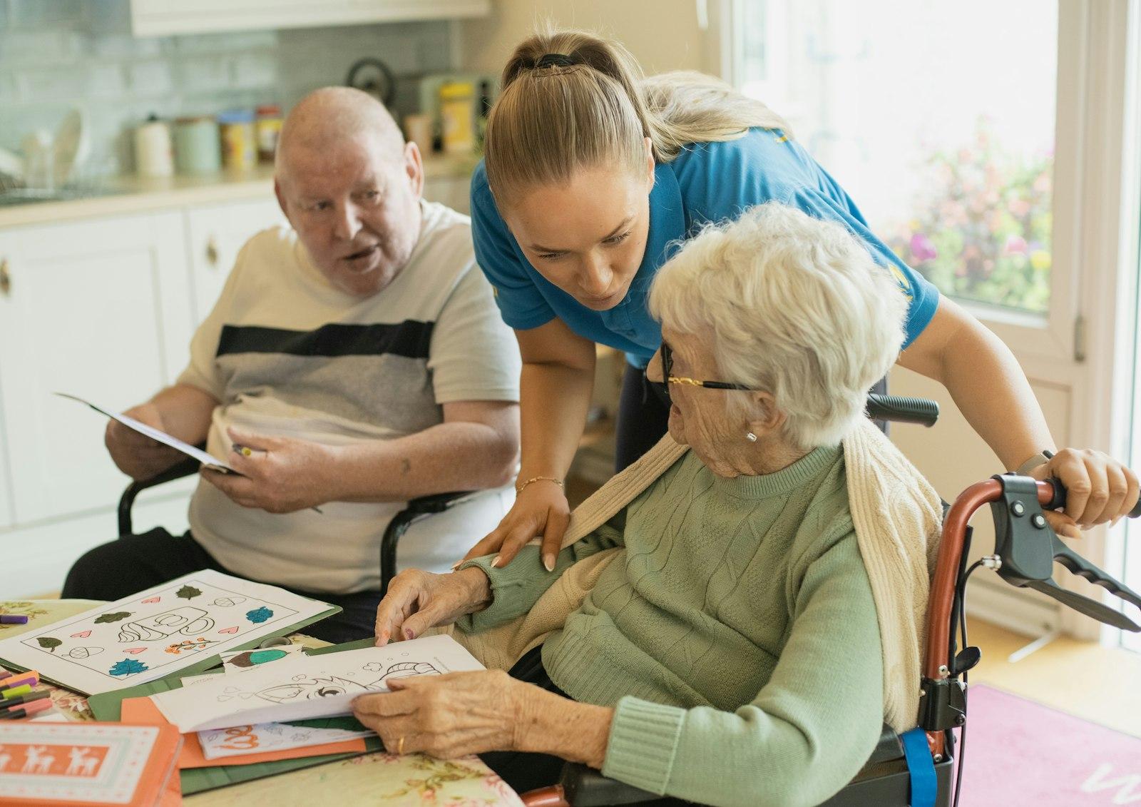 A support worker assists two residents during an activity