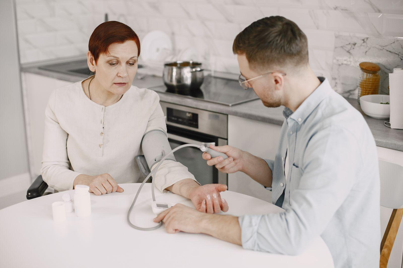 A support worker takes a person's blood pressure at home